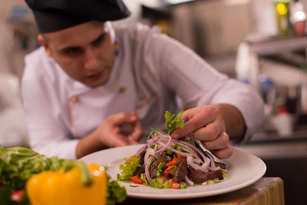 cozinheiro chefe decorando o prato de refeição preparada no prato na cozinha comercial do restaurante