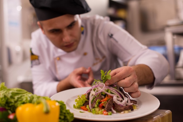 cozinheiro chefe decorando o prato de refeição preparada no prato na cozinha comercial do restaurante