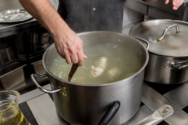 Cozinheiro chefe que coocking o khinkali georgian ou o wonton japonês.