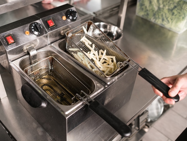 Cozinheiro do aluno trabalhando em seu verão ou emprego paralelo preparando comida em um restaurante. Treinamento de habilidades de chef