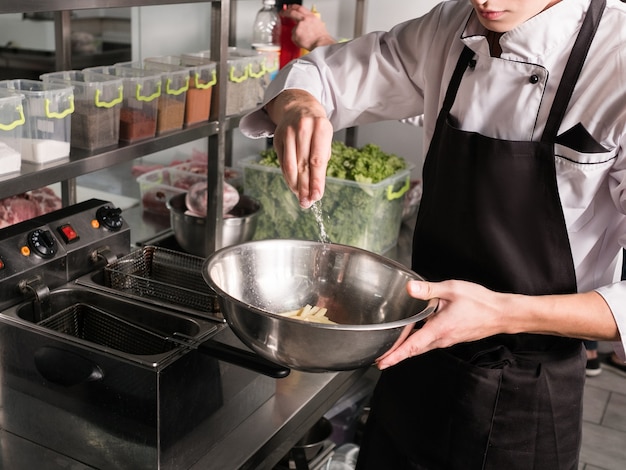 Cozinheiro do aluno trabalhando em seu verão ou emprego paralelo preparando comida em um restaurante. Treinamento de habilidades de chef