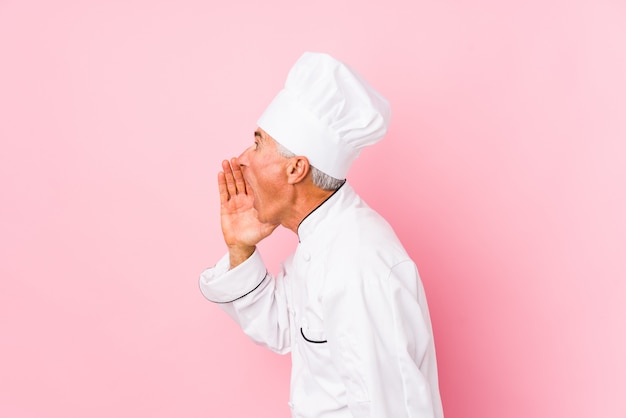 Cozinheiro envelhecido médio homem isolado gritando e segurando a palma da mão perto da boca aberta