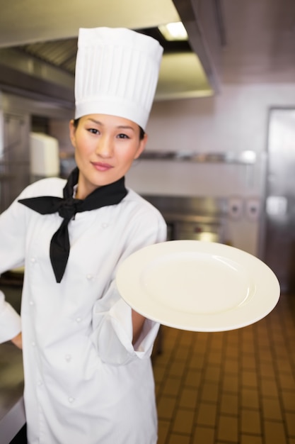 Cozinheiro feminino segurando um prato vazio na cozinha