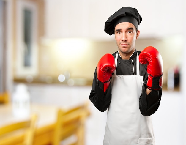 Cozinheiro jovem estressado usando luvas de boxe