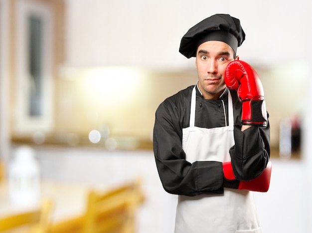 Cozinheiro jovem estressado usando luvas de boxe