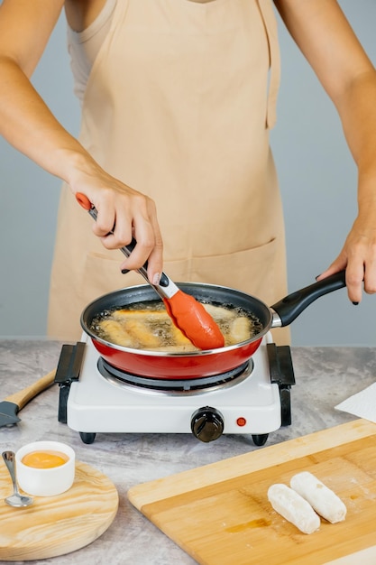 Cozinheiro latino-americano preparando e fritando aperitivo latino de tequenos venezuelanos