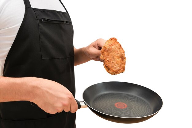 Cozinheiro masculino com uma frigideira e carne frita em suas mãos em um fundo branco e isolado