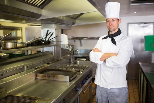 Cozinheiro masculino sério com os braços cruzados na cozinha