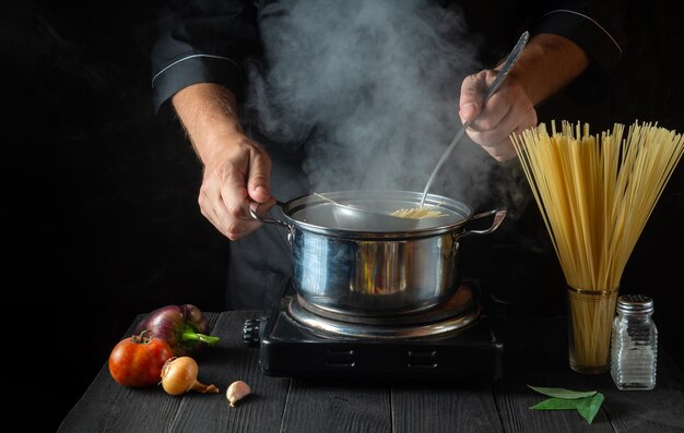 Cozinheiro prepara macarrão italiano em uma panela com legumes