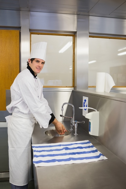 Cozinheiro sorridente lavando as mãos