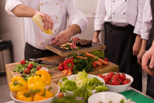 Cozinheiros e chefs de equipe profissional preparando refeições na cozinha movimentada do hotel ou restaurante