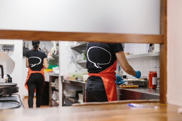 Cozinheiros em um restaurante preparando comida para viagem. Os recipientes usados são compostáveis.