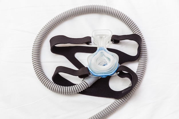 CPAP Maske, die mit dem Bügel und Schlauch verbindet, die auf ein Bett legen