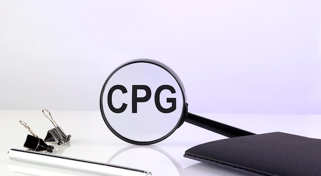 CPG Consumer Packaged Goods Konzept Lupenglas mit Text mit Notizbuch und Stift