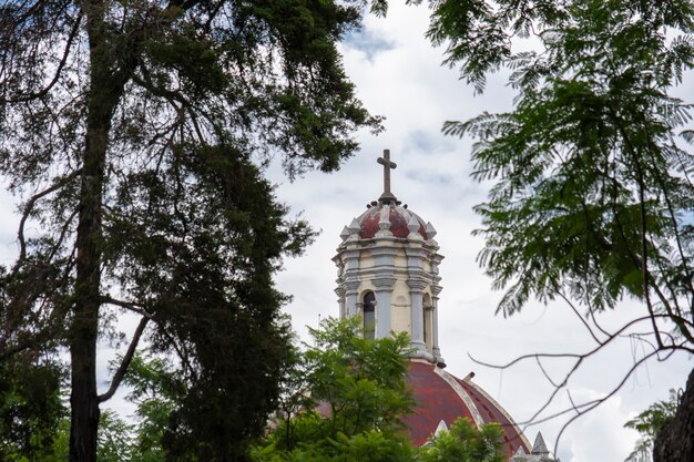 Cpula de iglesia con una cruz y las nubes y cielo azul al fondo