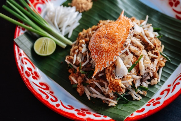 Crab Pad Thai serviert mit Limetten, Schalotten, Sojasprossen. zerkleinertes Erdnuss- und Chilipulver.