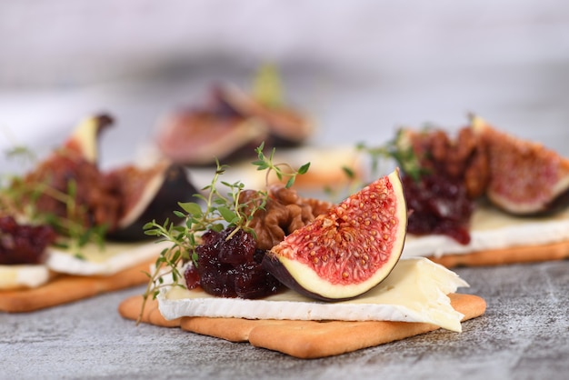 Cracker mit einer Scheibe Camembert und Marmelade mit Feigen