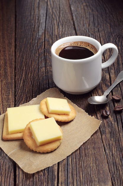 Cracker mit Käse und heißem Kaffee auf rustikalem Holztisch