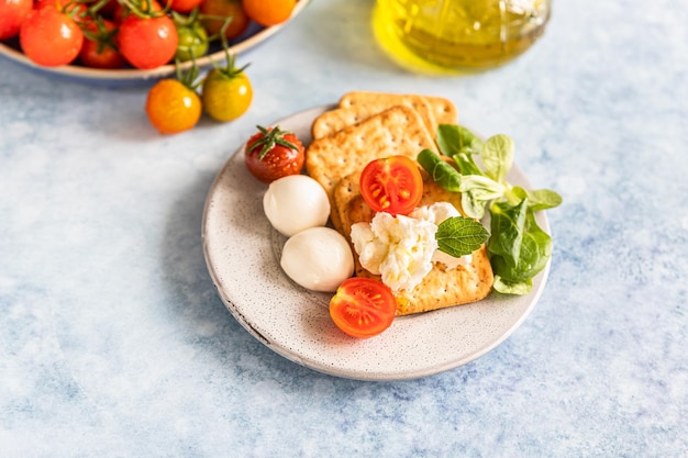 Cracker mit Kirschtomaten, grünem Salat und Mozzarella