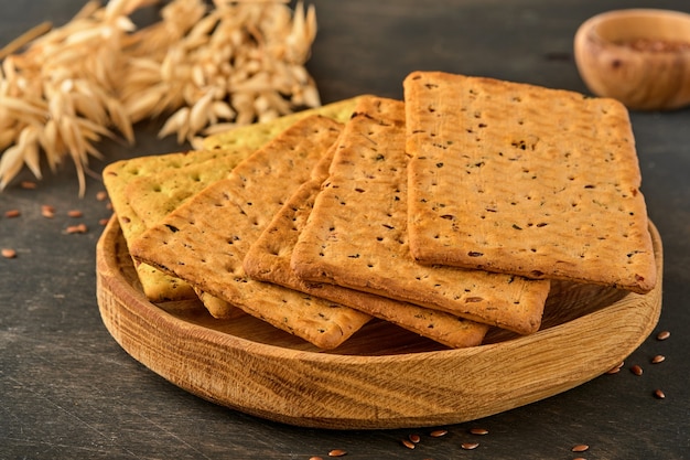 Cracker mit Leinsamen und Haferkleie rechteckige Form auf dunklem Holztisch. Snack für die richtige Ernährung.