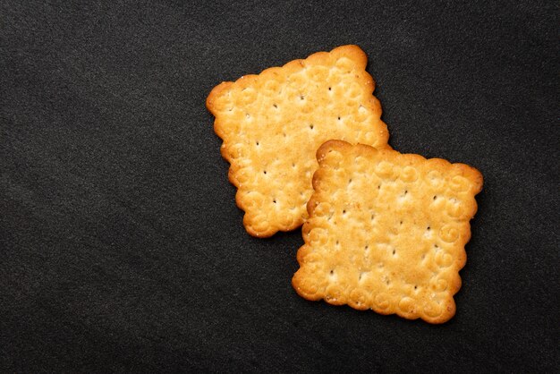 Cracker mit Sesam auf schwarzem Hintergrund.