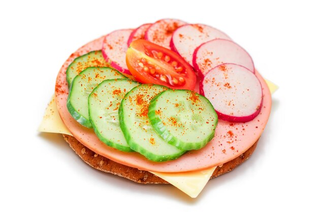 Cracker-Sandwich mit frischer Gurke, Käse, Wurst, Rettich und Tomate isoliert