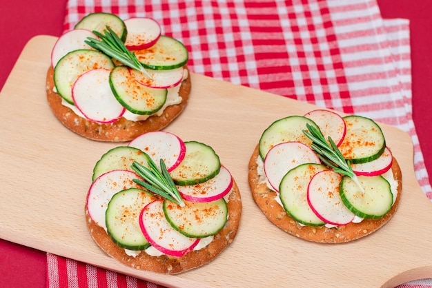 Cracker-Sandwich mit Frischkäse, frischer Gurke und Rettich