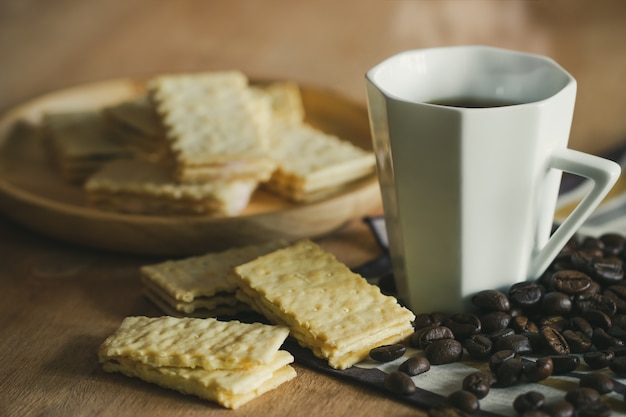 Cracker werden auf Holzteller und Kaffeetasse gelegt