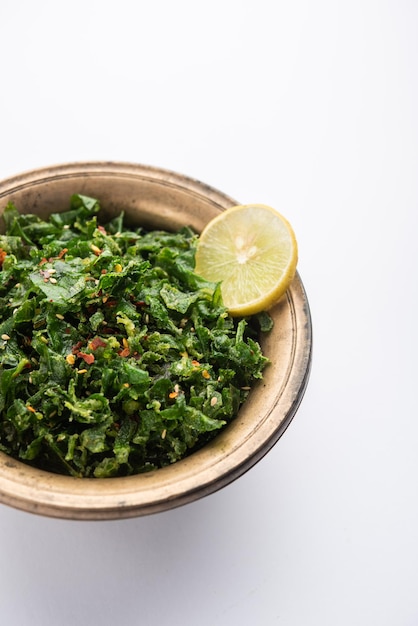 Crackling Spinach ou Crispy Palak é uma entrada indiana, servida em uma tigela ou prato com uma rodela de limão