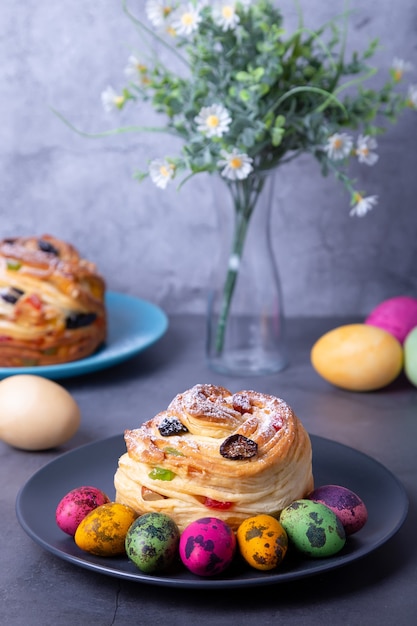 Craffin (cruffin) com passas, nozes e frutas cristalizadas. pão de páscoa kulich e ovos pintados. feriado da páscoa. fechar-se.