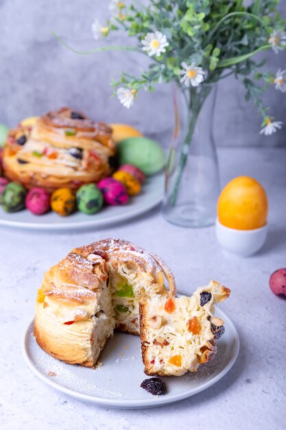 Foto craffin (cruffin) mit rosinen, nüssen und kandierten früchten. osterbrot kulich und bemalte eier. osterferien. nahansicht.