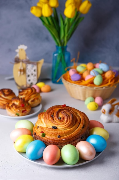 Craffin Cruffin con pasas y frutas confitadas Pan de Pascua tradicional Kulich y huevos pintados sobre un fondo gris Vacaciones de Pascua Primer plano enfoque selectivo