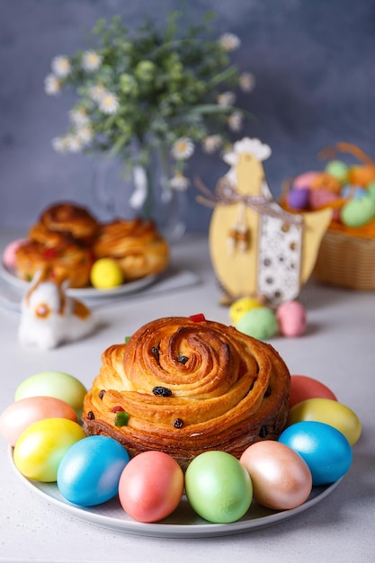 Craffin Cruffin con pasas y frutas confitadas Pan de Pascua tradicional Kulich y huevos pintados sobre un fondo gris Vacaciones de Pascua Primer plano enfoque selectivo