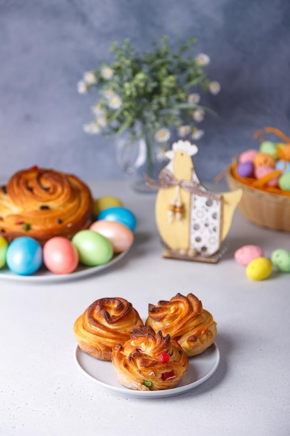 Craffin mini Cruffin com passas e frutas cristalizadas Pão de Páscoa tradicional Kulich No fundo é um grande cruffin e ovos pintados em um fundo cinza Feriado de Páscoa Closeup foco seletivo