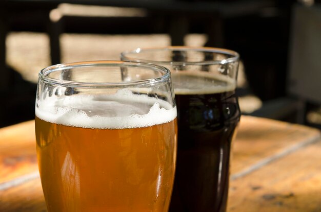 Craft-Bier auf einem Holztisch im Freien 1 Glas Lager oder Lager und ein Glas Stout oder Porter