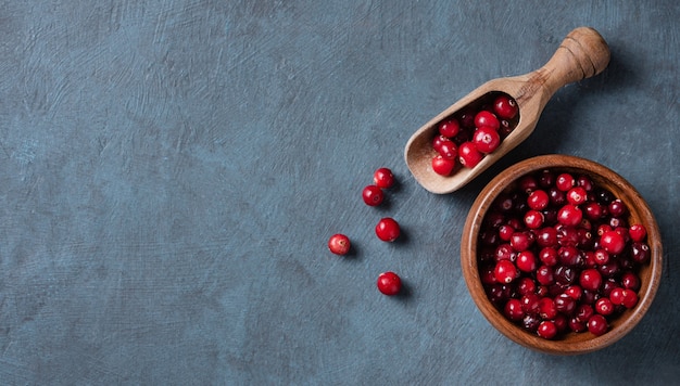 Foto cranberries frescas e doces em uma tigela de madeira sobre um fundo de madeira azul escuro. vista superior e espaço de cópia