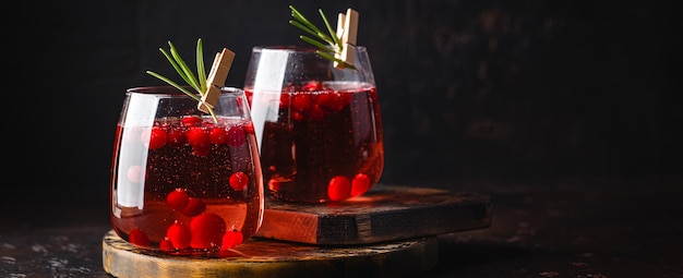 Cranberry Cocktail mit Rosmarin in zwei Gläsern auf Weiß