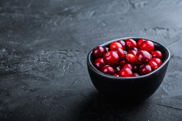 Cranberry, reife rote Beere in Schüssel mit Platz für Text, auf schwarzem Hintergrund.