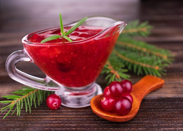 Cranberry-Sauce in einer gläsernen Sauciere auf einem hölzernen Hintergrund