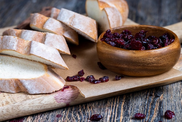 Cranberry und geschnittenes weiches frisches Baguette auf einem Schneidebrett und Tisch