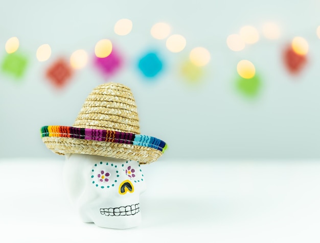 Cráneo decorado con sombrero mexicano sobre fondo blanco con luces desenfocadas Día de los muertos en México