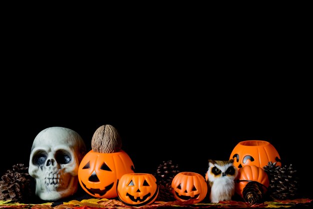 Cráneo humano de Halloween, calabazas de Halloween en una vieja mesa de madera delante de un fondo negro con espacio libre para texto. Conceptos de Halloween. Feliz día de Halloween.