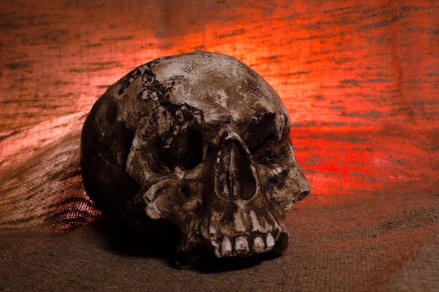 Cráneo humano con luz roja sobre fondo marrón textil Concepto de decoraciones de Halloween