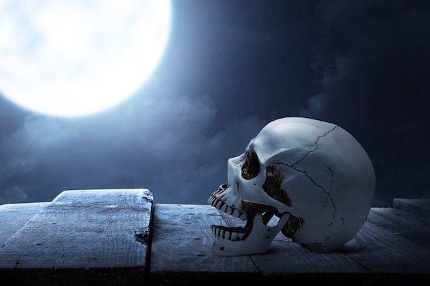 Foto cráneo humano en mesa de madera con el fondo de la escena nocturna