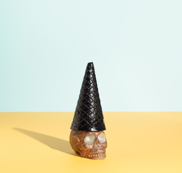 Cráneo marrón con sombrero de bruja hecho de cono de helado negro Concepto espeluznante Halloween o Santa Muerte