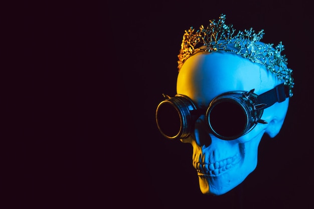 Crânio humano em uma coroa e óculos steampunk com luz neon azul amarela colorida