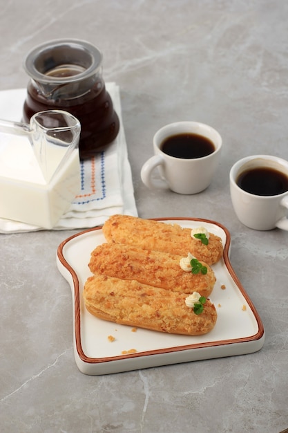 Craquelin Eclair, delicioso postre francés de hojaldre con motivos de tigre en la parte superior (Craquelin), cubierto con hojas de menta y crema. Servido con Café