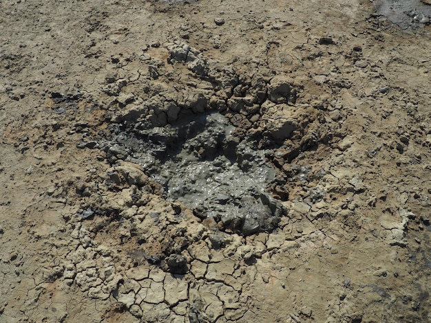 Cráter con arcilla curativa volcánica gris Un agujero con una masa amorfa prominente de las profundidades de la tierra Erupción de lodo y gas Temryuk Rusia Superficie del suelo agrietada Textura de grietas de flujo de lodo