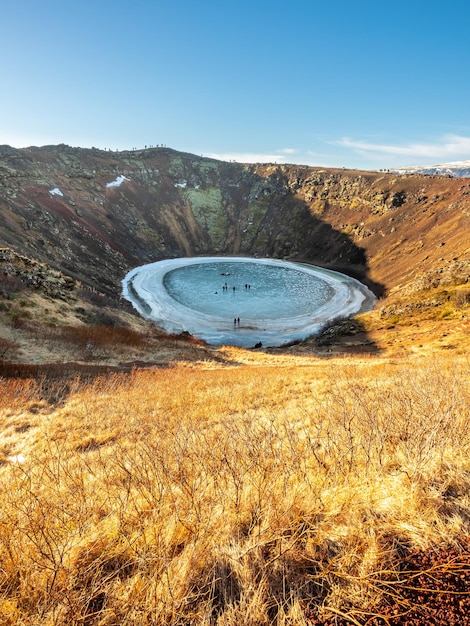 El cráter Kerid, un enorme cráter volcánico tranquilo, se convierte en un lago de hielo duro en Islandia a lo largo de la carretera del círculo dorado