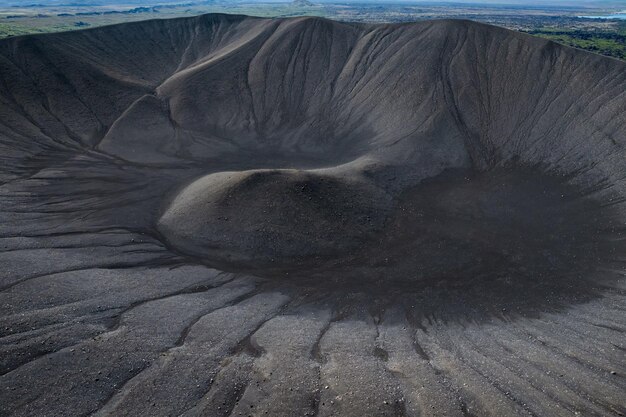 Cráter del volcán con arena negra y paisaje escénico en el fondo